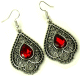 Boucles d'oreilles pendantes en metal argente cisele serties de pierres rouge