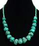 Collier ethnique artisanal imitation pierres difformes turquoises separees de perles en metal et compose d'autres perles vertes