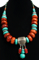 Collier ethnique artisanal disques oranges et pierres turquoises agremente de breloques et d'armatures gravees argentees